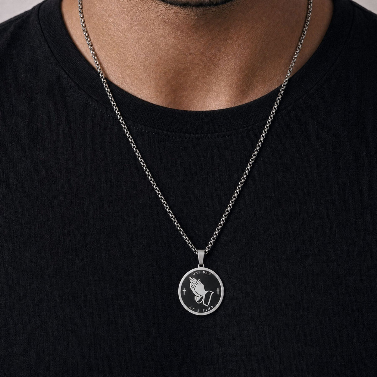 Religiøs halskæde med hænder i bøn til mænd, i rustfrit stål, kristen medaljon og sindsrobønnen indgraveret på bagsiden